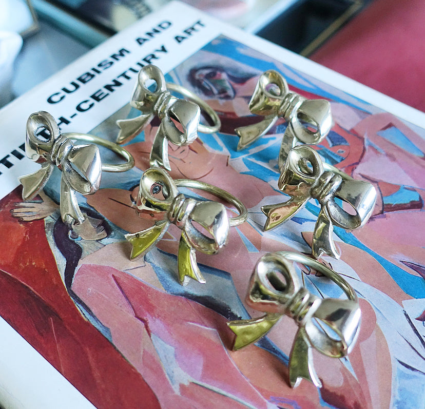 Set of six Hollywood regency brass bow napkin rings