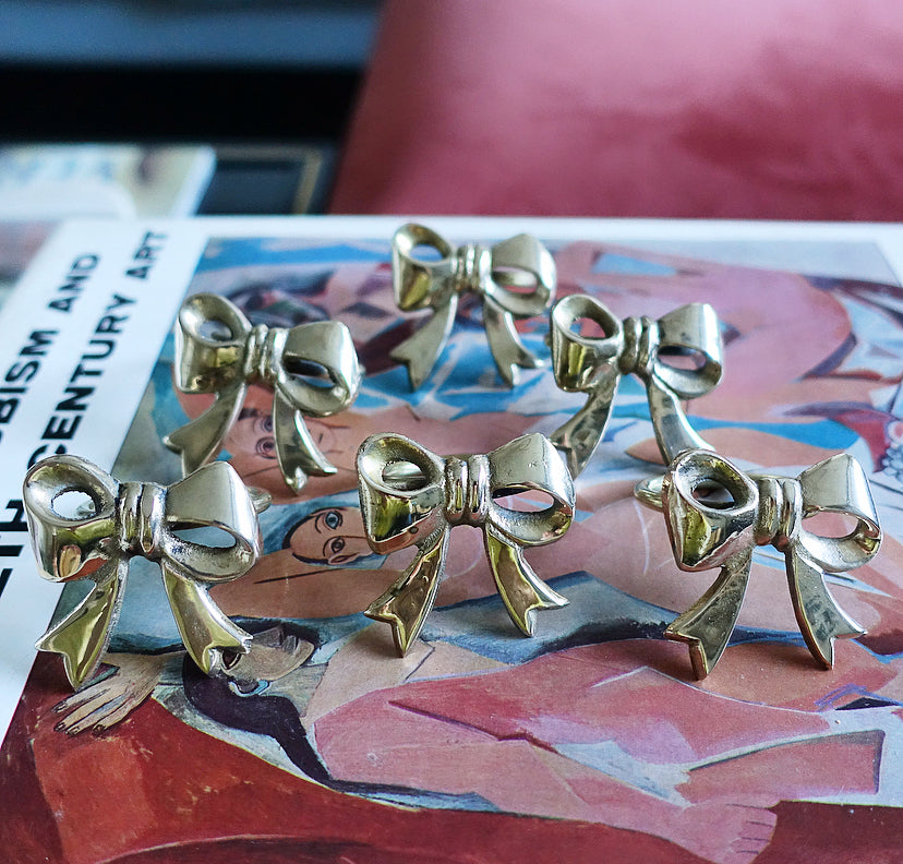 Set of six Hollywood regency brass bow napkin rings