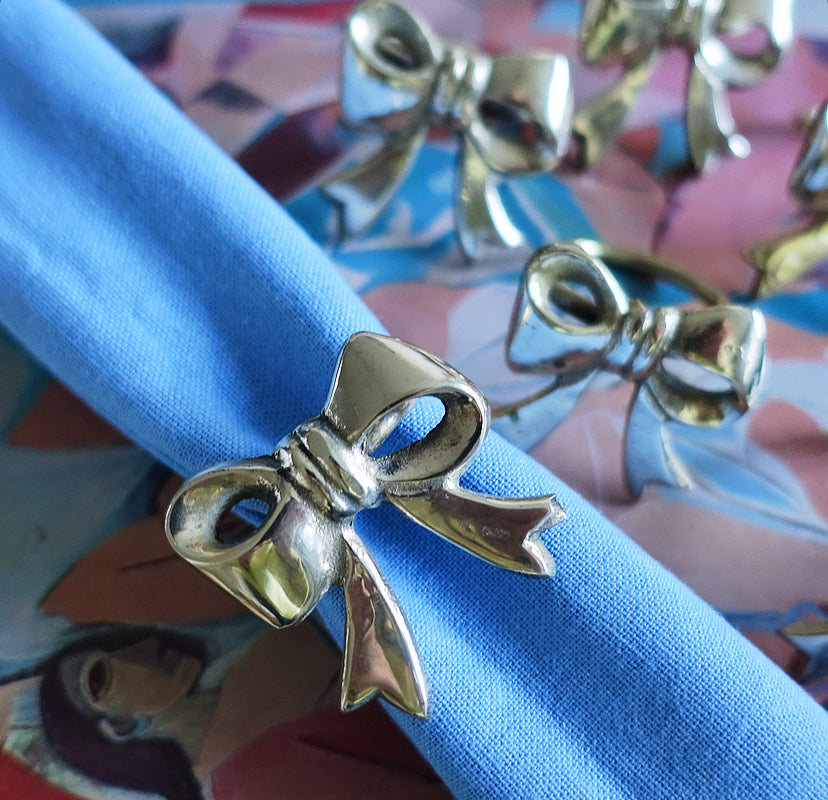 Set of six Hollywood regency brass bow napkin rings