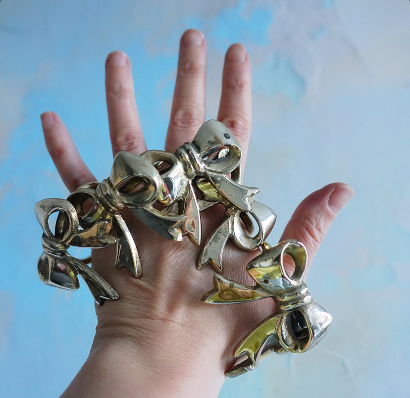Set of six Hollywood regency brass bow napkin rings