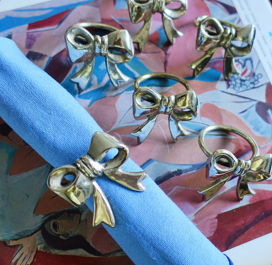 Set of six Hollywood regency brass bow napkin rings