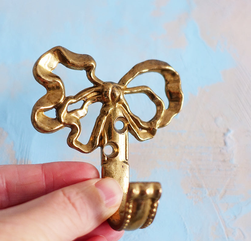 Set of four small brass bow hooks